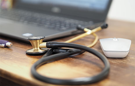 Detailansicht Stethoskop, im Hintergrund Laptop