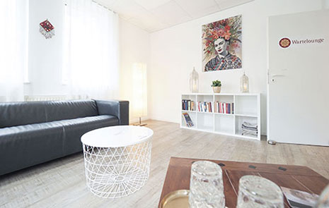 Unsere Wartelounge mit Sofa, Getränke und Bücherregal